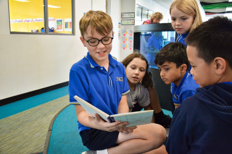Elementary kids reading a book together